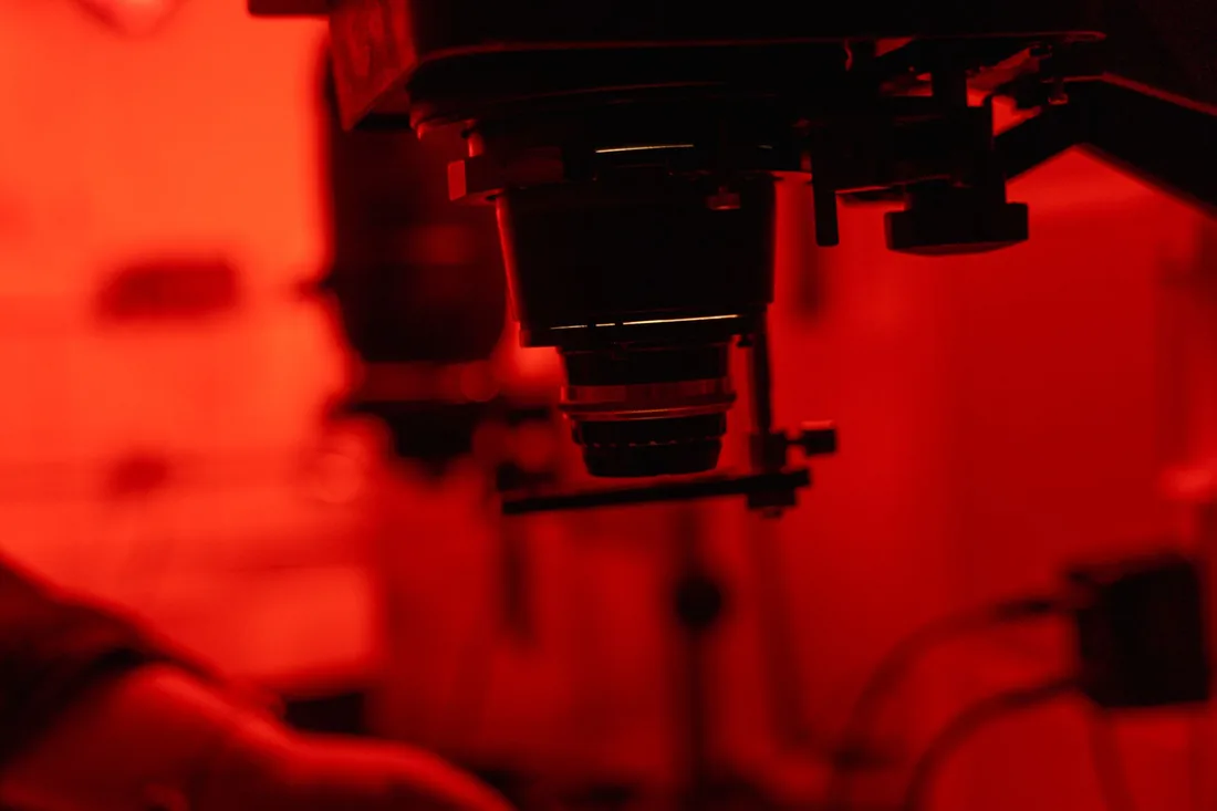Ampliadora y material de laboratorio en una cámara oscura iluminada con luz de seguridad roja